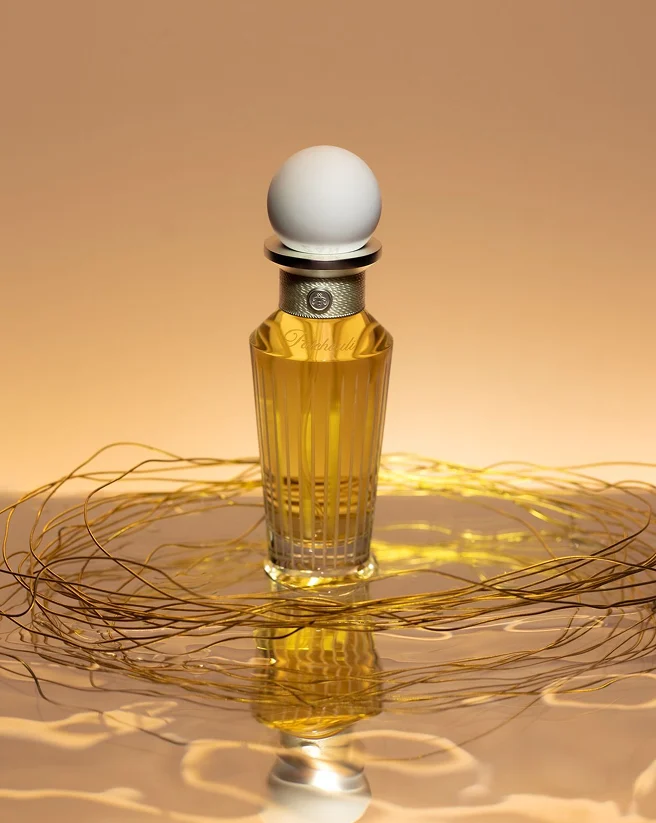 Zan fragrance bottle on a reflective golden surface