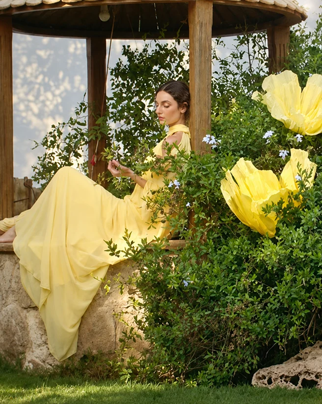 Woman in a yellow dress posed among flowers