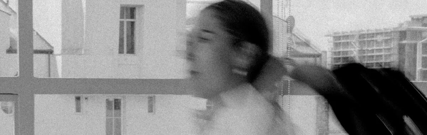 Blurred black-and-white portrait of a person in motion by a window